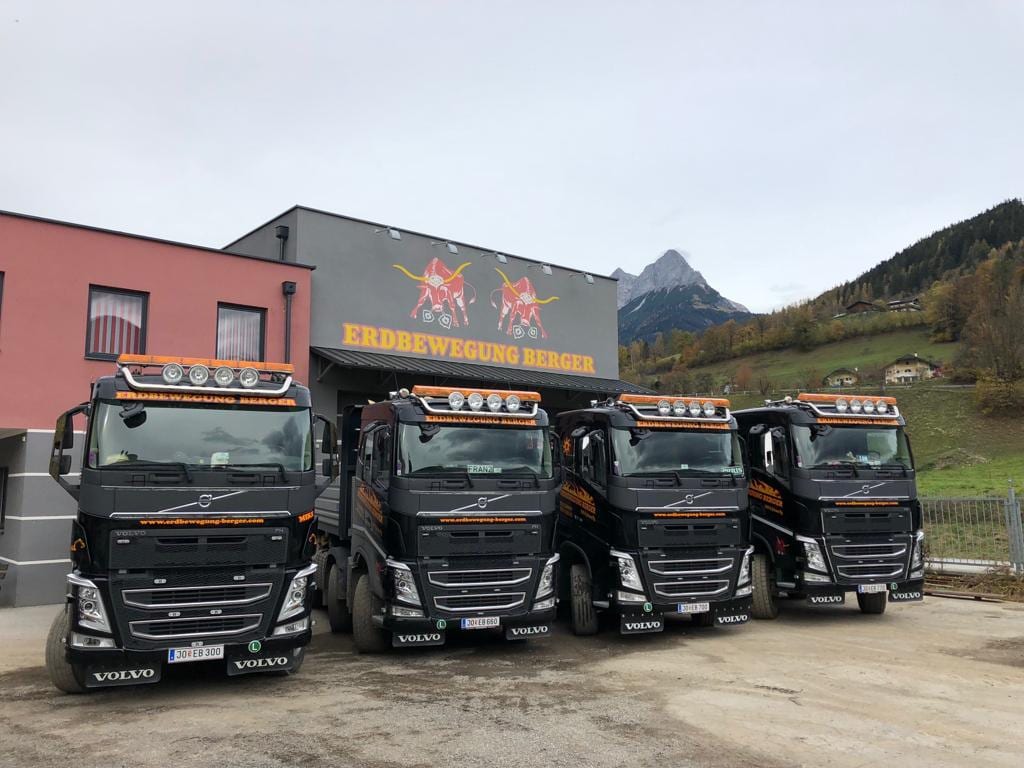 Vier Volvo-Sattelzugmaschinen der Berger GmbH vor dem Firmengebäude in Pfarrwerfen, dahinter das Tennengebirge